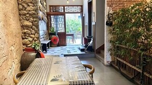 A table with a checkered tablecloth, a stone wall, and a bamboo plant in the background. - Wenchang Haiju Diary Homestay (Wenchang)