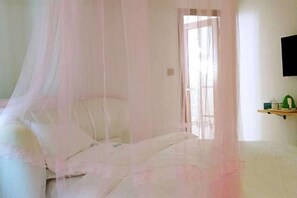 A bedroom with a bed, a bedside table, a wall-mounted TV, and a window with a view. - Wenchang Haiju Diary Homestay (Wenchang)