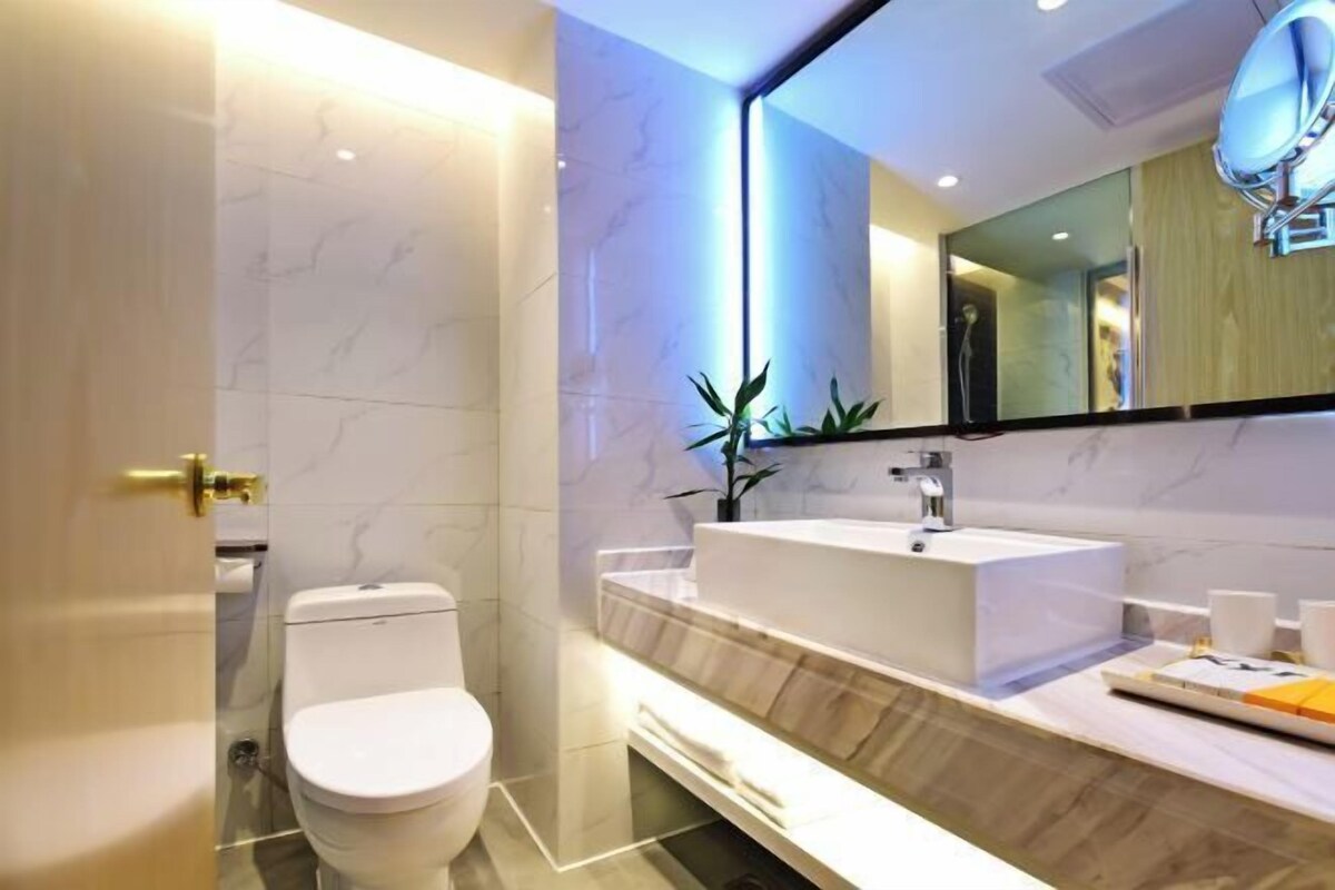 Een moderne badkamer met een wit toilet, een grote spiegel en een wastafelmeubel met een wastafel.