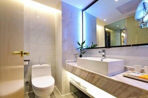 Un baño moderno con inodoro blanco, un espejo grande y un tocador con lavabo.