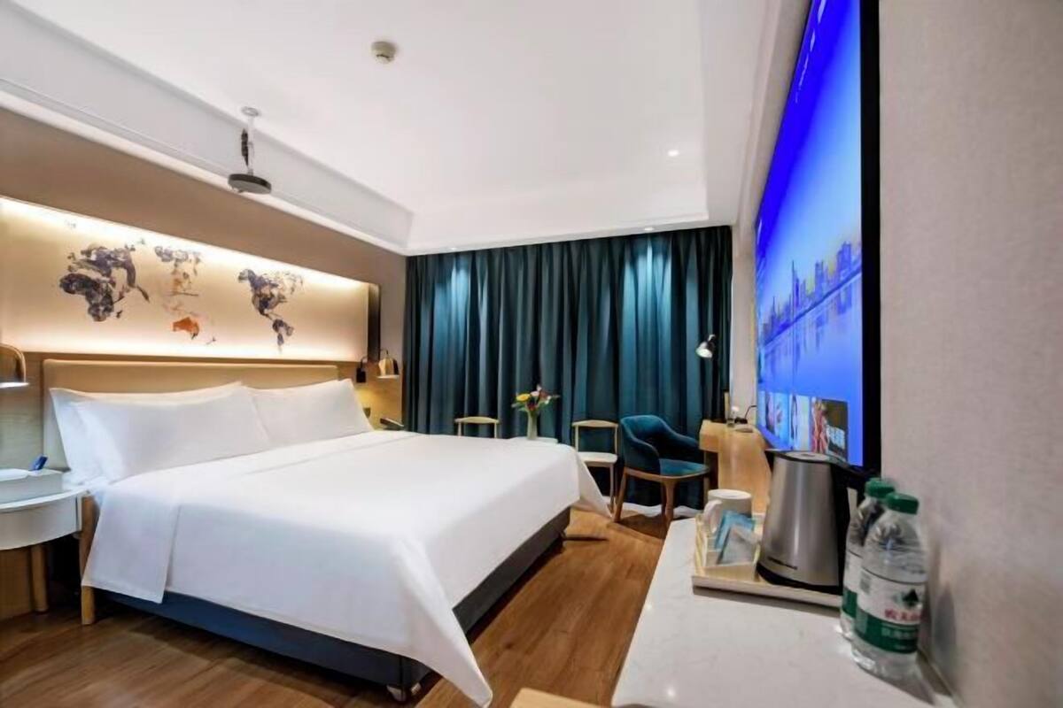 A hotel room with a bed, a desk, a chair, a coffee maker, and a TV.