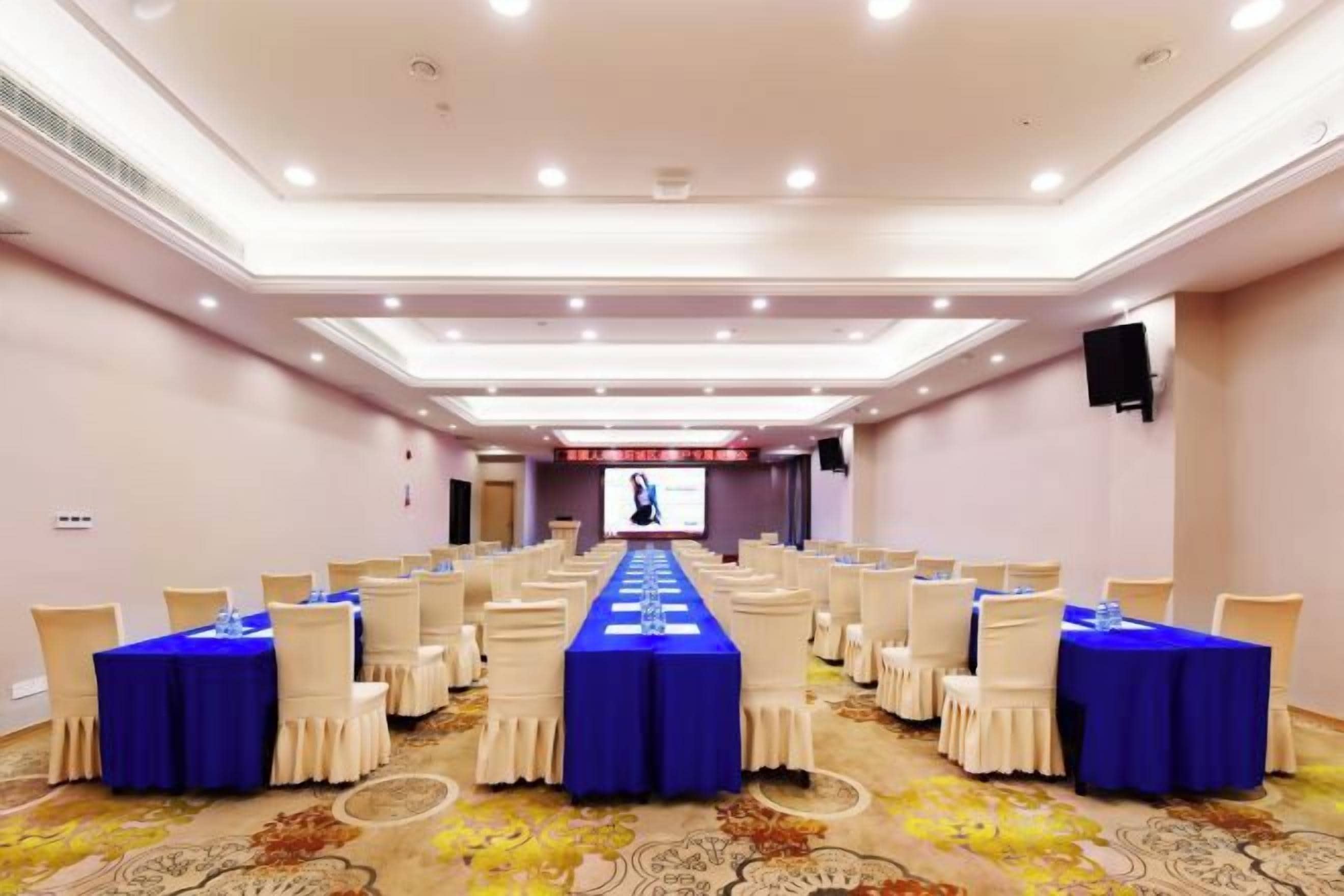 A conference room with a long table, chairs, and a screen at the front.