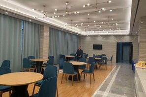 A conference room with round tables and chairs, a flat-screen TV, and a modern ceiling design.