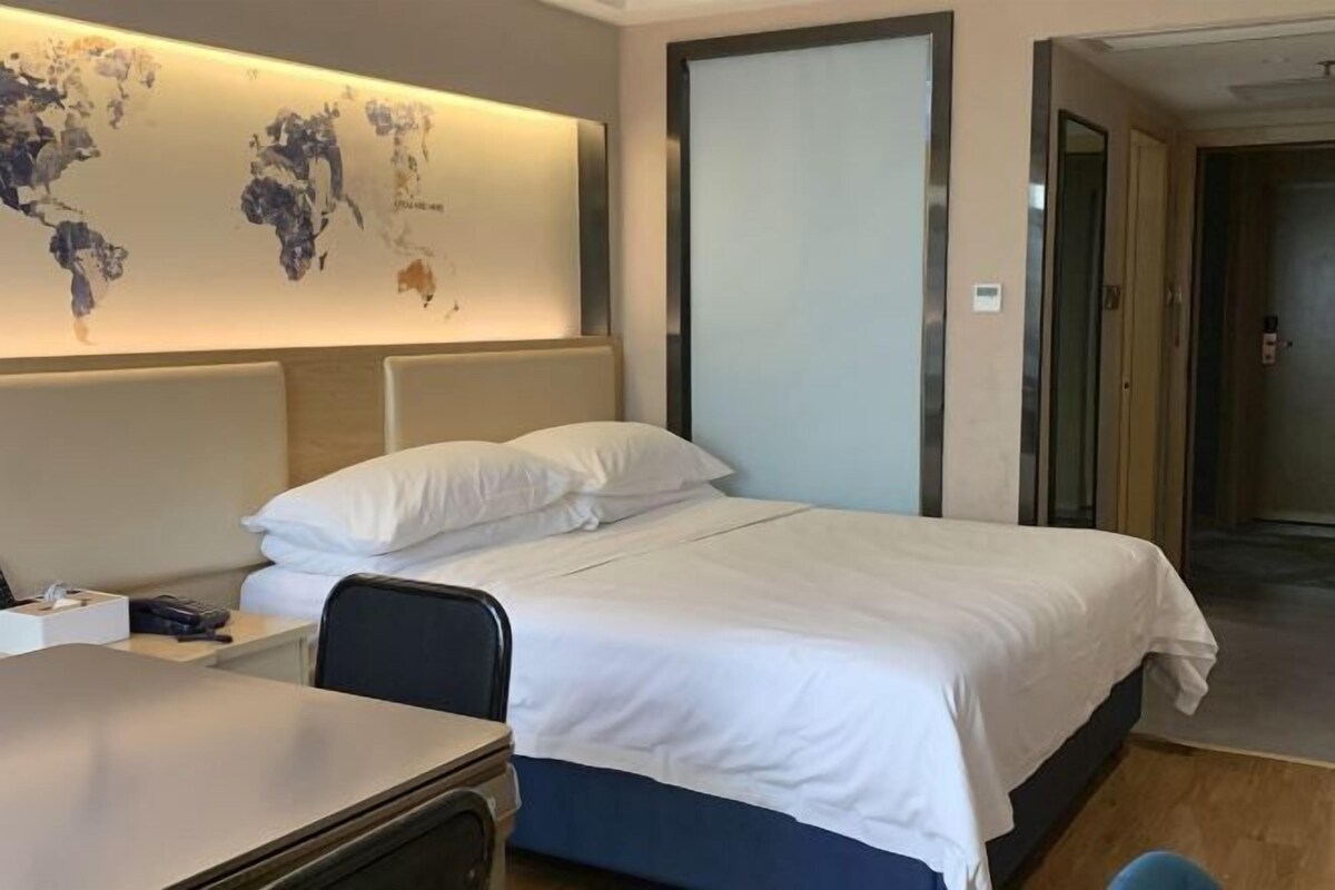 Een hotelkamer met een bed, een bureau en een wereldkaart aan de muur.