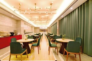 En restaurant med flere borde og stole, en disk med rød facade og et loft med hængende lamper.