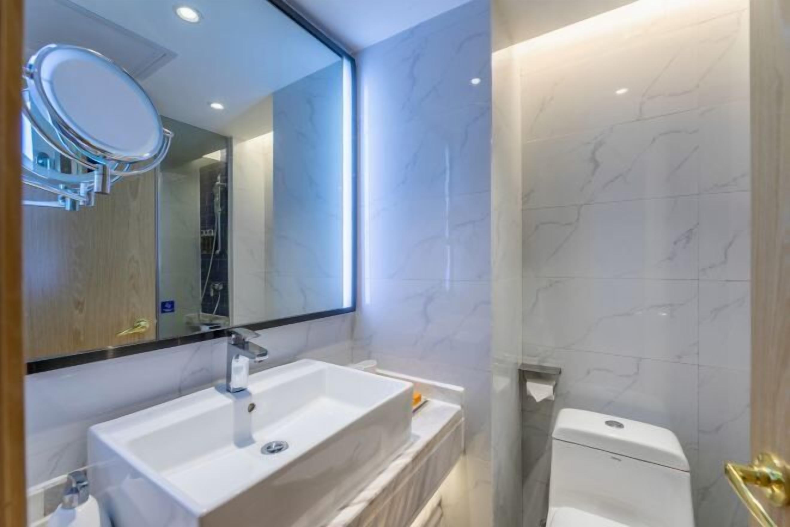 A modern bathroom with a white sink, mirror, and toilet.