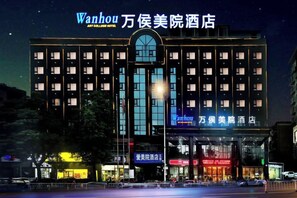 A hotel with multiple floors, a prominent entrance, and illuminated signage.