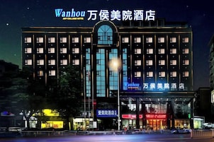 Um hotel com vários andares, entrada destacada e letreiros iluminados.