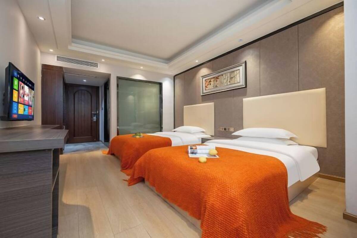 Habitación de hotel con dos camas, un escritorio y una televisión.