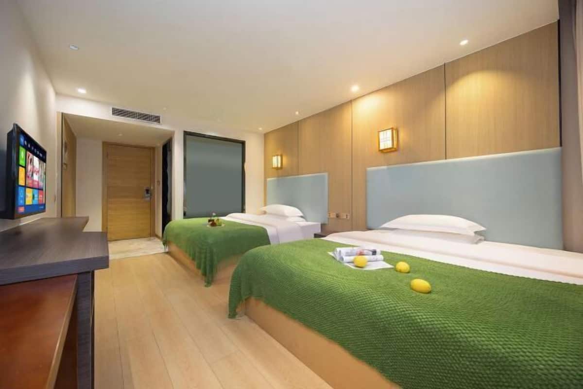 Habitación de hotel con dos camas, un escritorio y televisión.