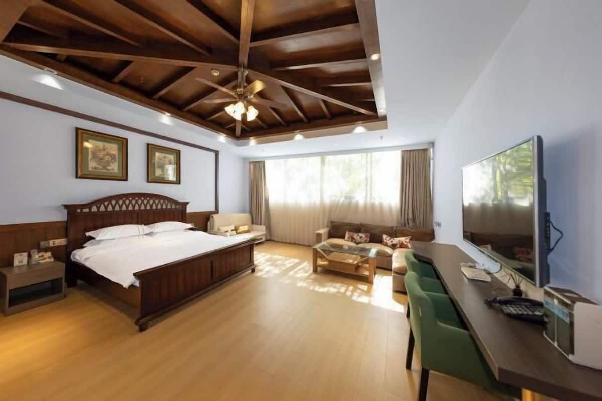 Un dormitorio con techo de madera, una cama, un sofá, un televisor y un escritorio.