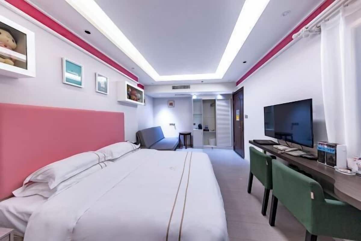 Una habitación de hotel con una cama, un escritorio, un televisor y una silla.
