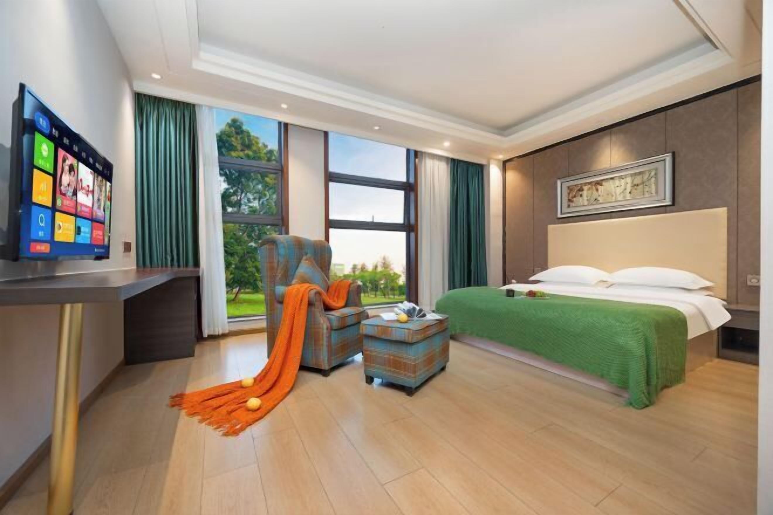 A modern hotel room with a bed, a desk, a chair, and a TV.