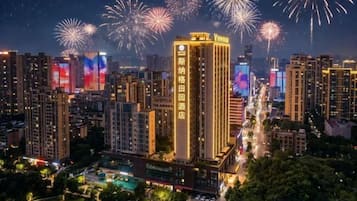 Un paisaje urbano con un hotel destacado, rodeado de edificios altos y una vista de fuegos artificiales en el cielo.