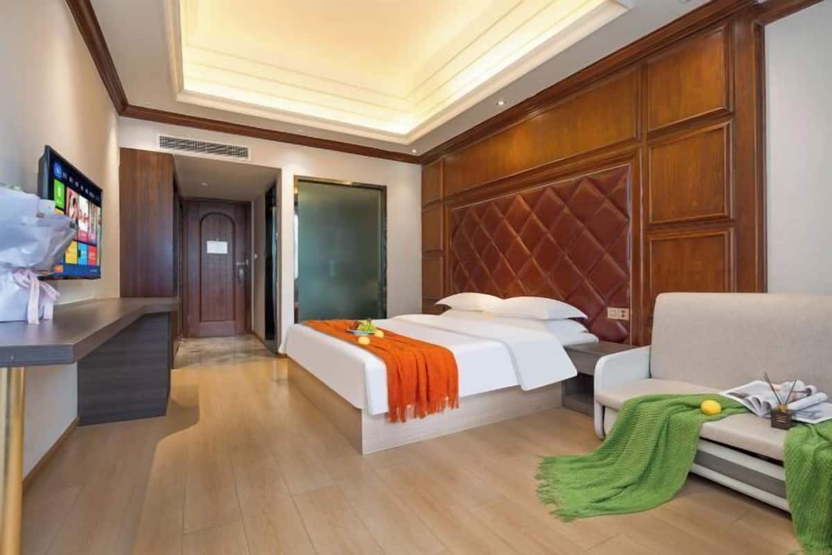 Habitación de hotel con cama, sofá, escritorio y televisión.