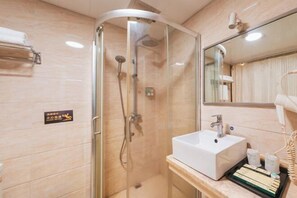 A modern bathroom with a glass-enclosed shower, a white sink, and a vanity with toiletries.