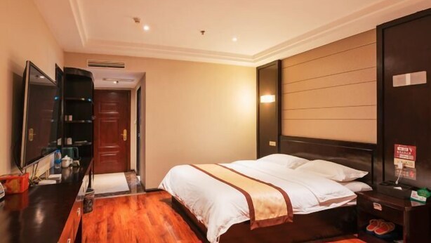 Ein Hotelzimmer mit einem Bett, einem Nachttisch aus Holz, einem Spiegel und einer Tür.