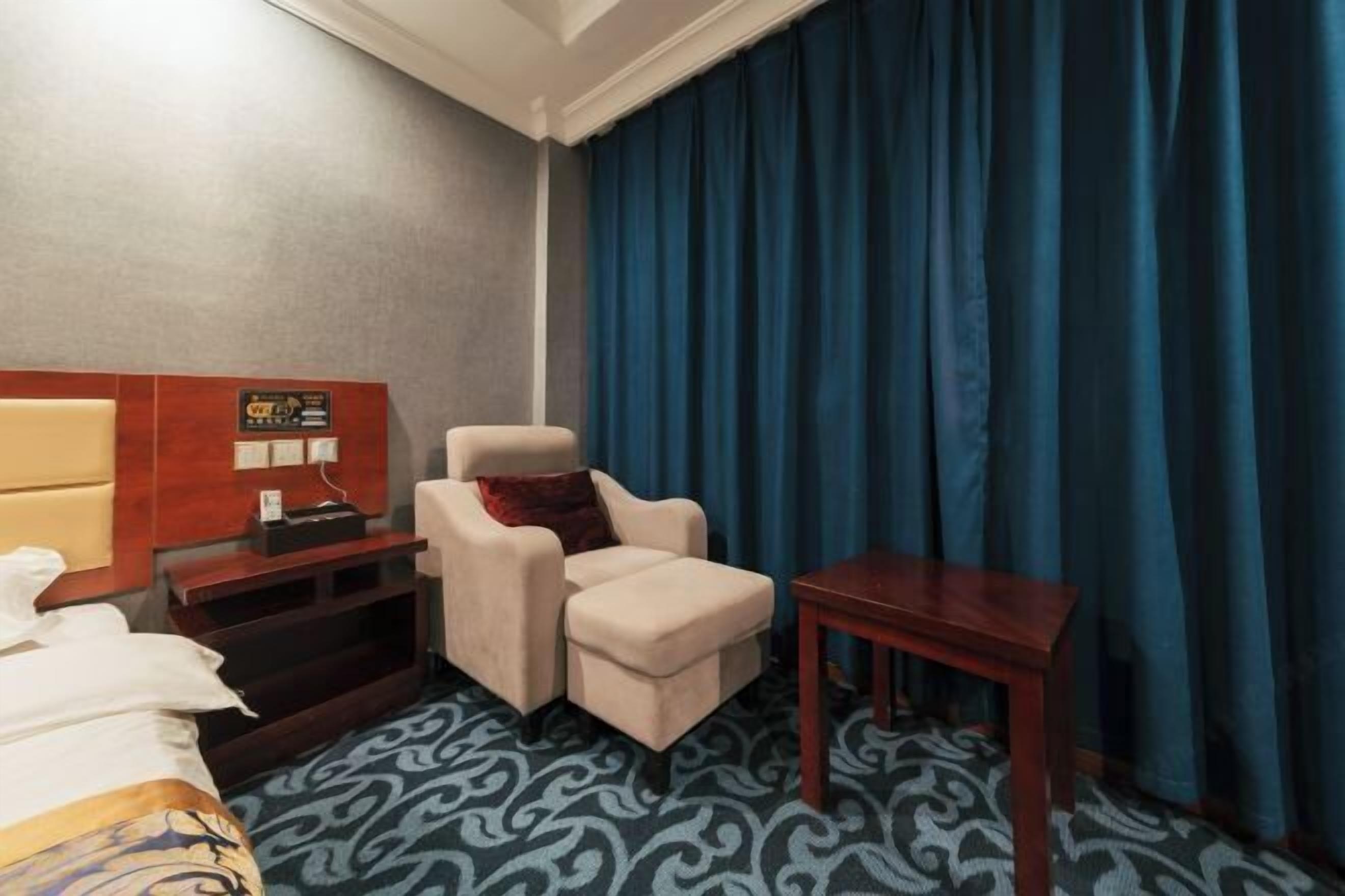 A hotel room with a bed, a chair, a small table, and a wall-mounted TV.