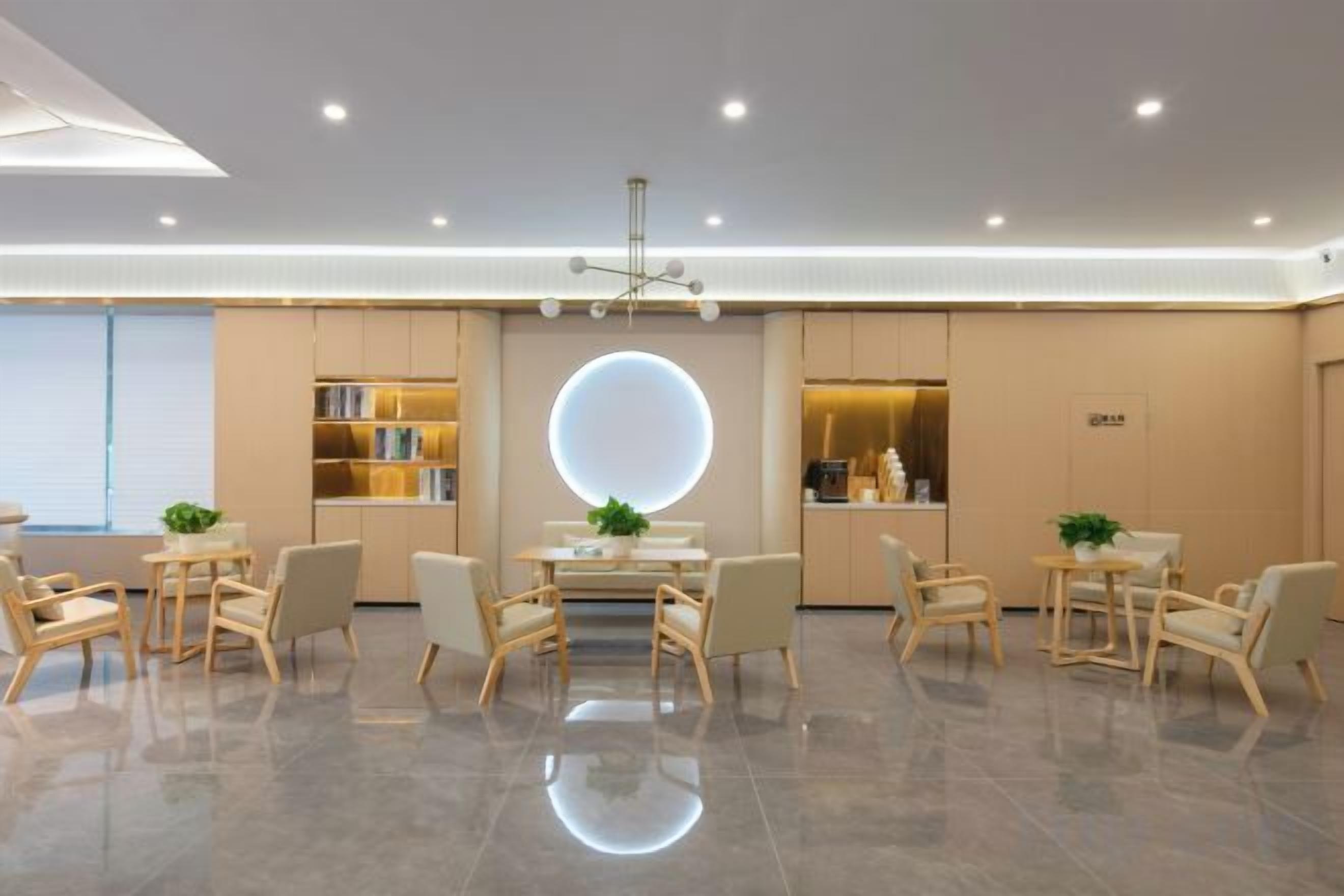 A modern hotel lobby with a central round table, seating arrangements, and a large illuminated circular feature on the wall.