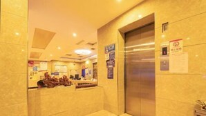 Eine Hotelhalle mit einer Rezeption, einem großen Aufzug und einem an der Wand befestigten Schild.