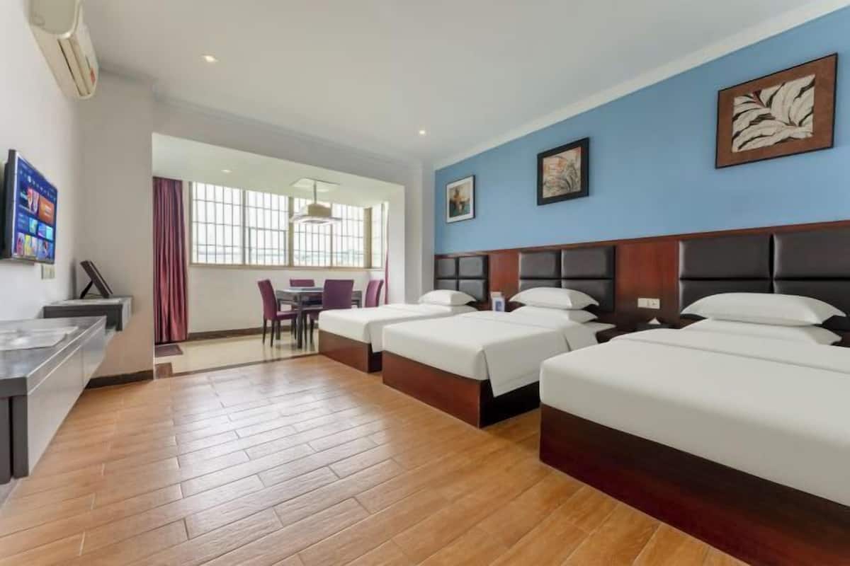 A hotel room with three beds, a dining area, and a view of the outside.