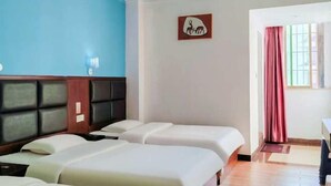 A hotel room with two beds, a blue wall, a wooden headboard, a framed picture, a window with curtains, and a small table. - Huaxuan Hotel (Jiangmen)