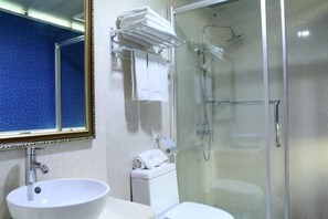 A bathroom with a sink, toilet, and a glass-enclosed shower area. - Huaxuan Hotel (Jiangmen)