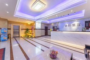A hotel reception area with a marble counter, a reception desk, and a small indoor plant. - Huaxuan Hotel (Jiangmen)