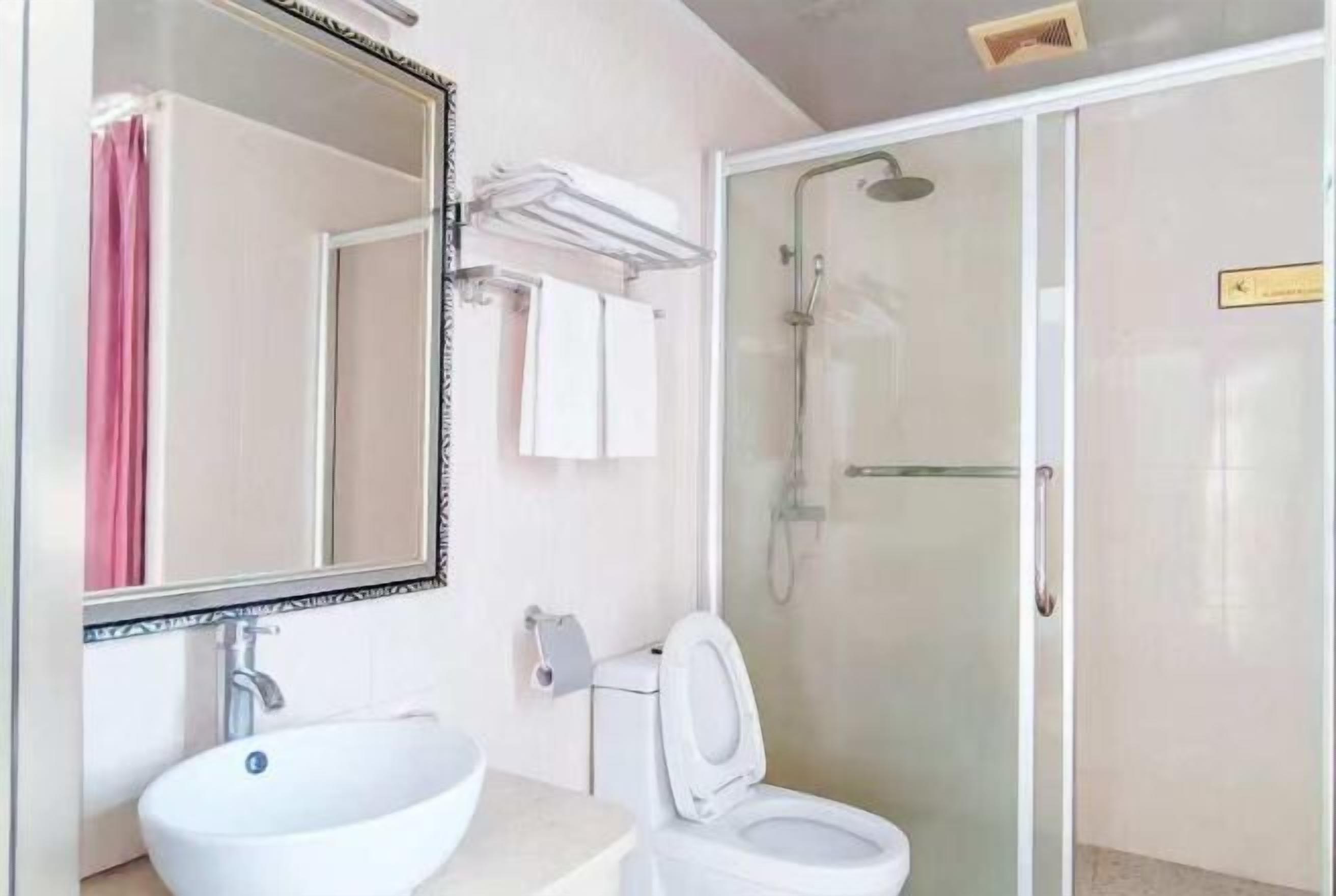 A bathroom with a white sink, toilet, and glass-enclosed shower.