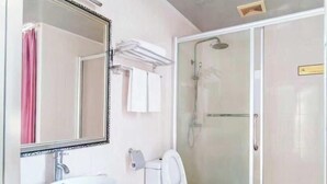 A bathroom with a sink, toilet, and glass-enclosed shower. - Huaxuan Hotel (Jiangmen)