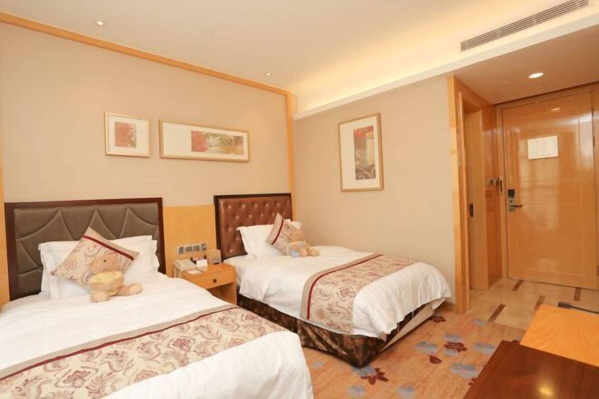 Une chambre d’hôtel avec deux lits, une armoire en bois et des œuvres d’art encadrées accrochées aux murs.