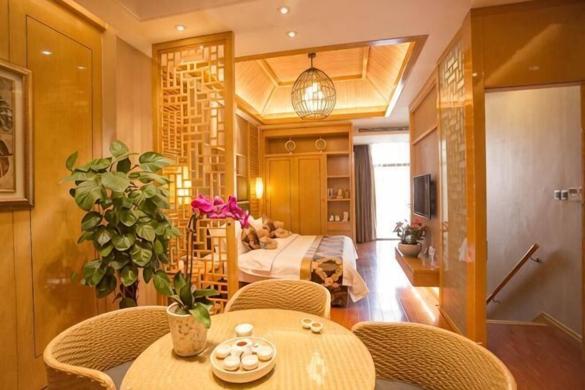 Une chambre d’hôtel comprenant un lit, une télévision, un coin repas avec une table et des chaises, et une plante décorative.