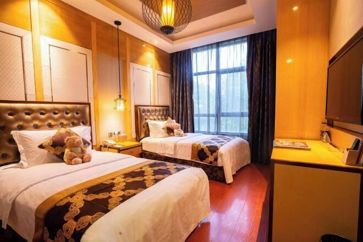 Une chambre d’hôtel avec deux lits, un bureau et une grande fenêtre.