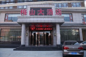Entrada de un hotel con un letrero que indica 'Meishanda Jiudian' y un letrero rojo con texto blanco.