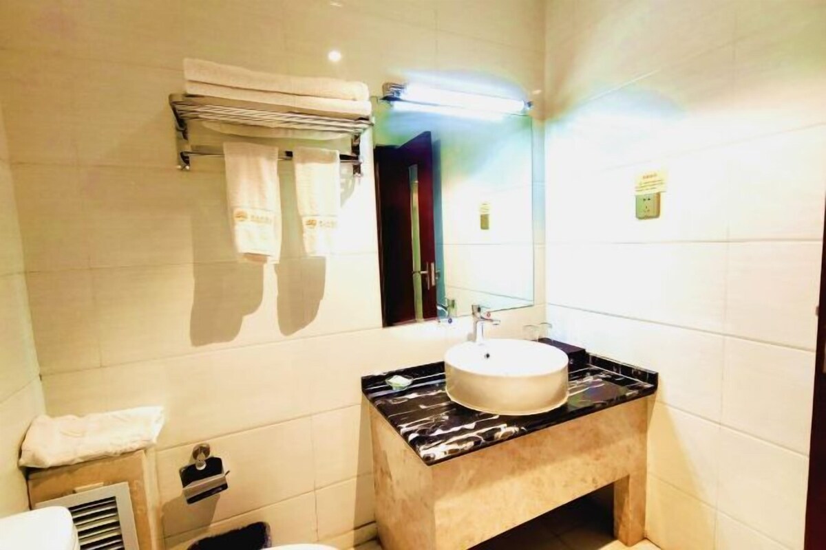 A bathroom with a marble countertop, a sink, and a mirror.