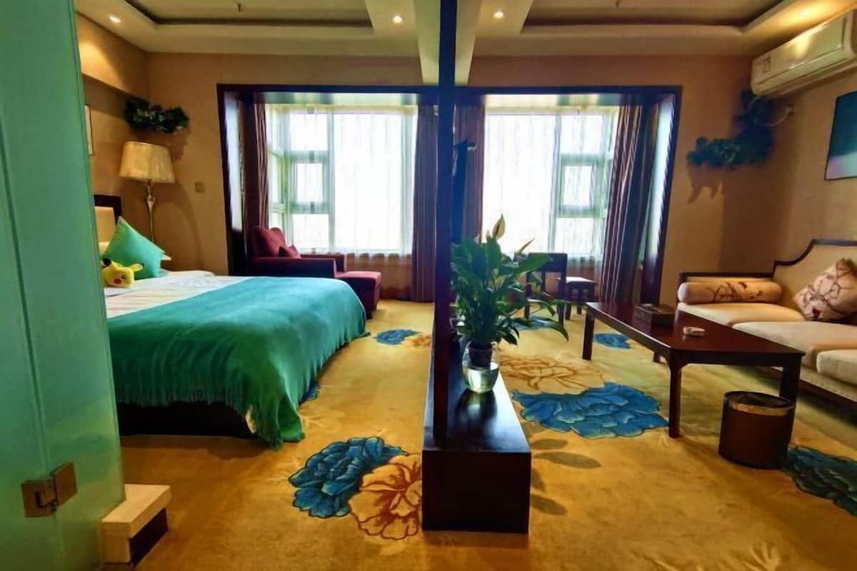 A hotel room with a bed, a sofa, a coffee table, and a plant.