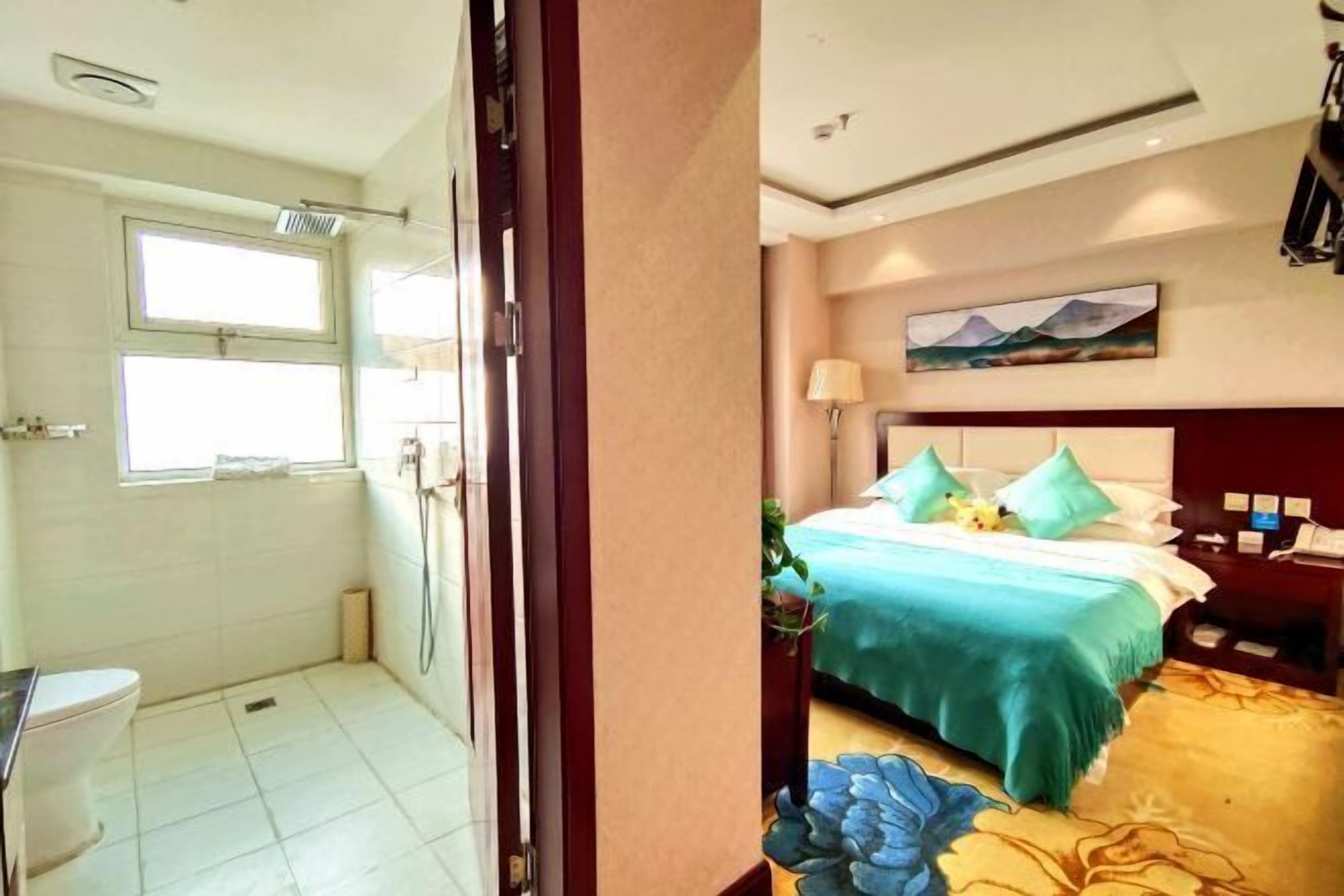 A hotel room with a bed, a nightstand, a lamp, and a painting on the wall.