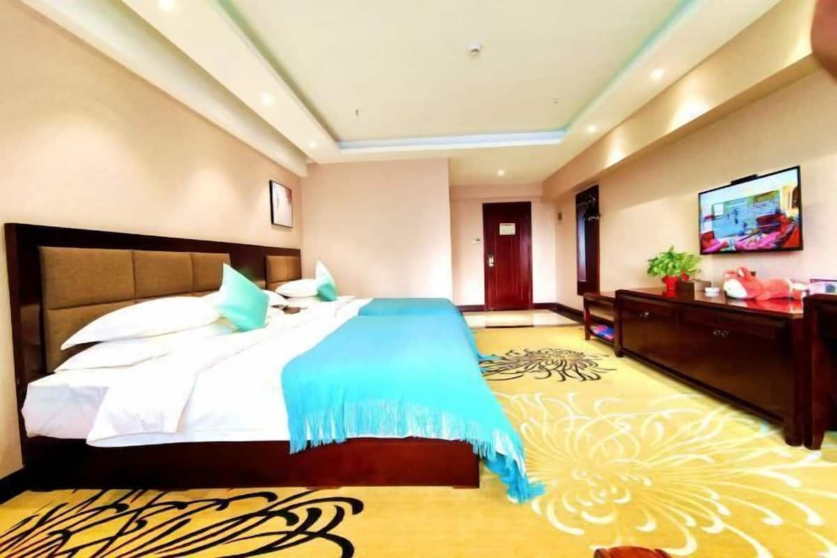A hotel room with a large bed, a wooden headboard, a flat-screen TV on the wall, and a decorative rug.