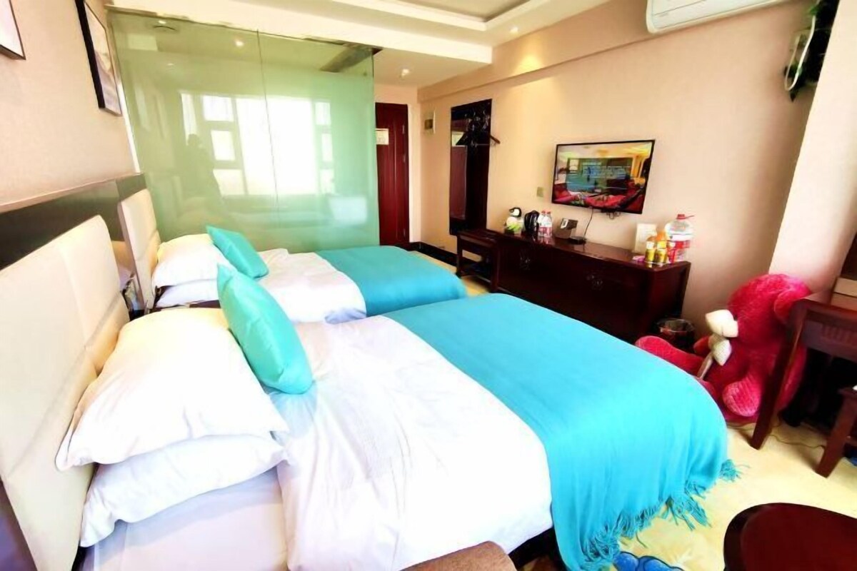 A hotel room with a bed, a desk, a chair, a mirror, and a window.