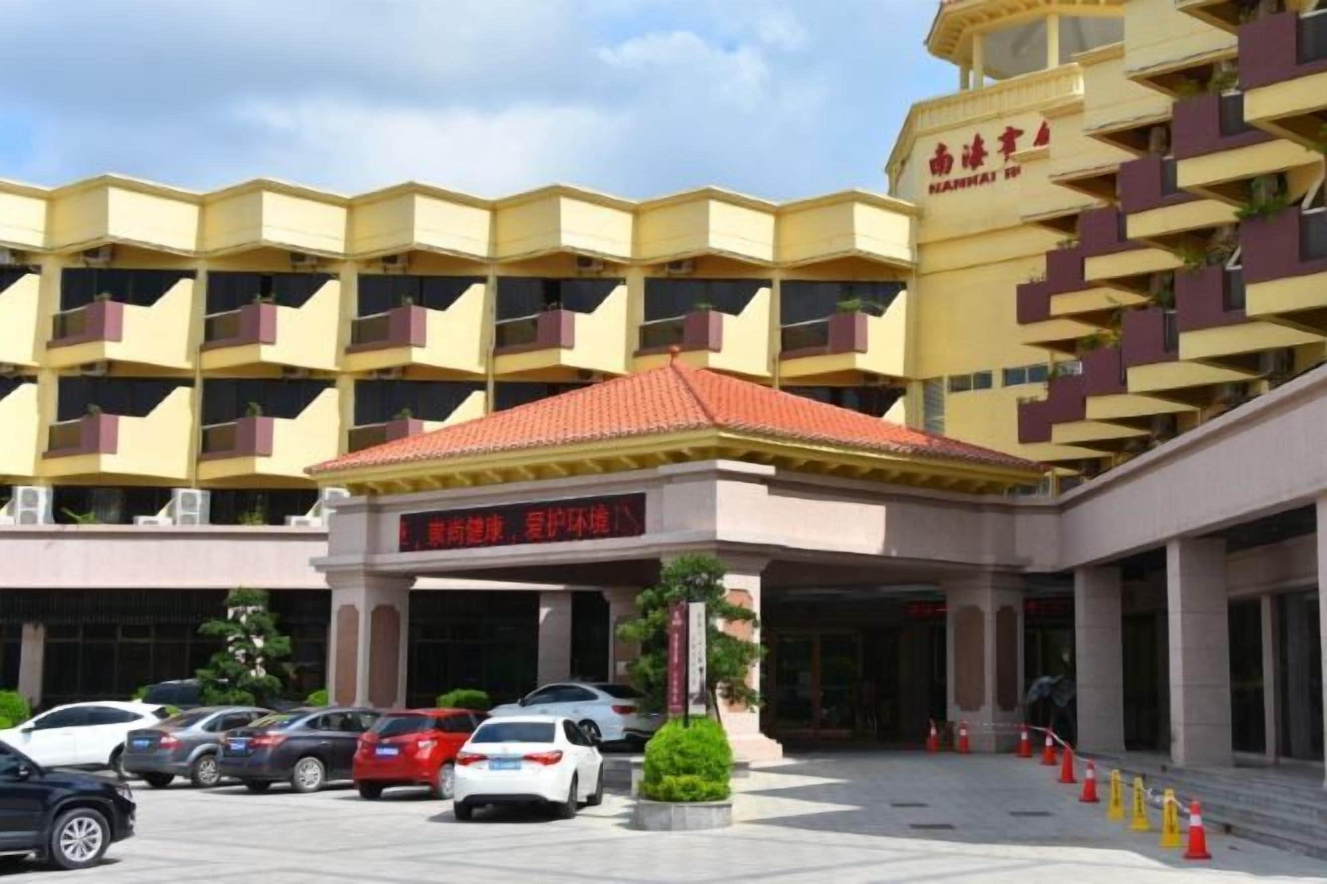 A hotel with a yellow facade, multiple balconies, and a red-roofed entrance.