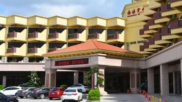 A hotel with a yellow facade, multiple balconies, and a red-roofed entrance.