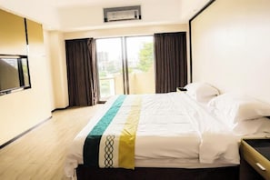 A hotel room with a bed, a TV, a window with curtains, and an air conditioning unit. - Nanhai Hotel (Zhanjiang)