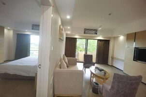 Una habitación de hotel con cama, sofá, una mesita, una silla y televisión.