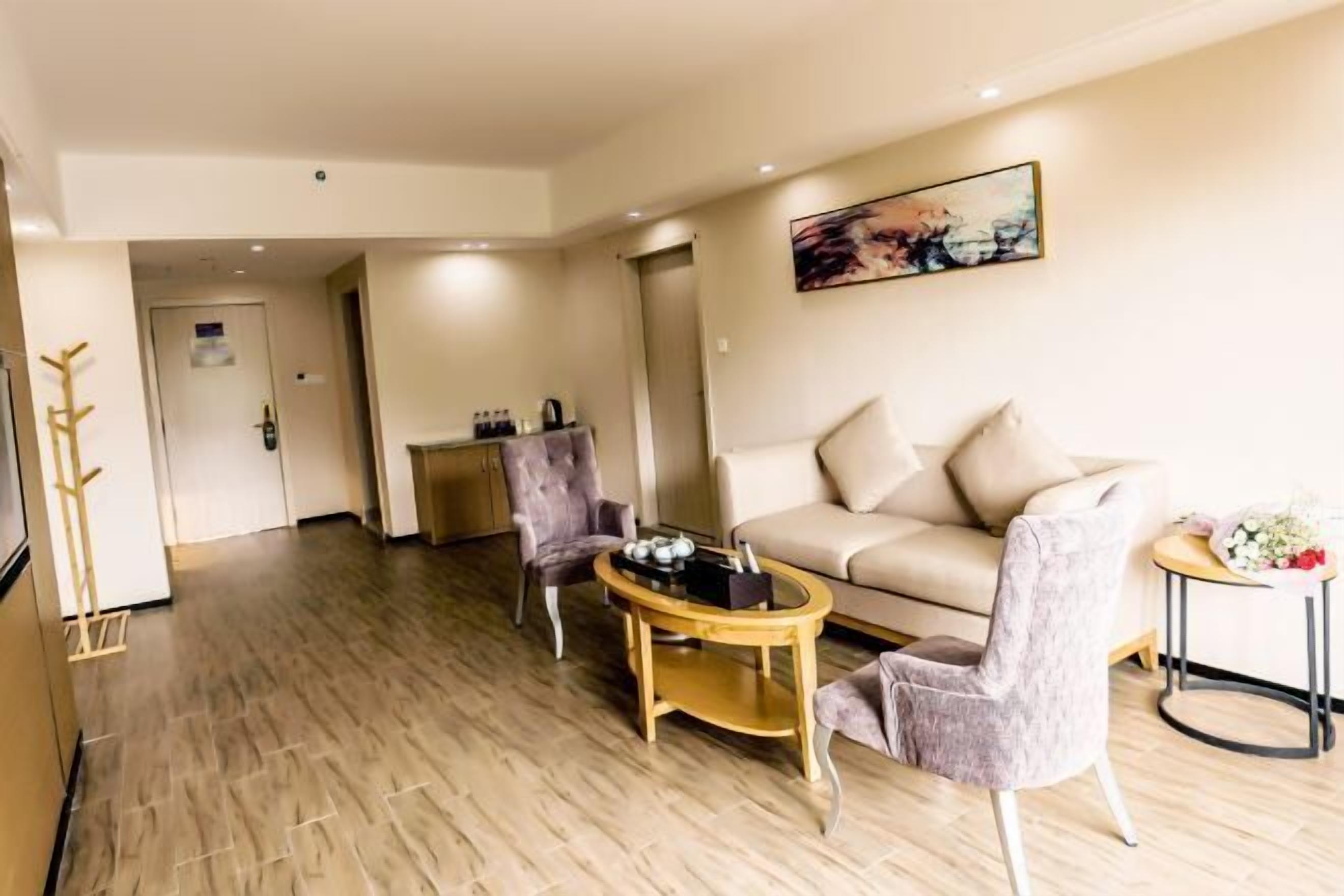 Una sala moderna con un sofá beige, dos sillones, una mesa de centro y una mesita auxiliar con flores.