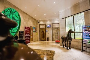 A lobby with a large green sculpture, a horse statue, and a digital screen. - Nanhai Hotel (Zhanjiang)
