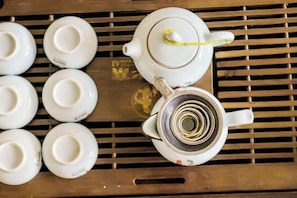 A white teapot with a yellow string on a tray with six white cups. - Nanhai Hotel (Zhanjiang)