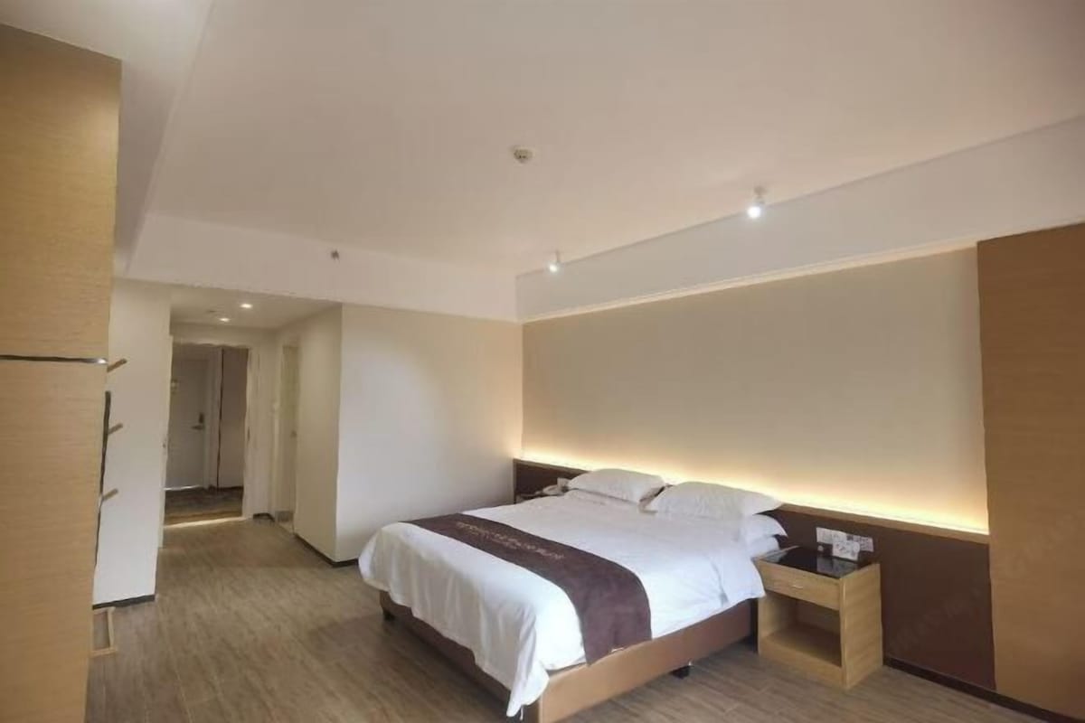 A hotel room with a bed, bedside table, and a wardrobe.