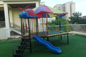 A playground with a slide, climbing steps, and a netted enclosure. - Nanhai Hotel (Zhanjiang)