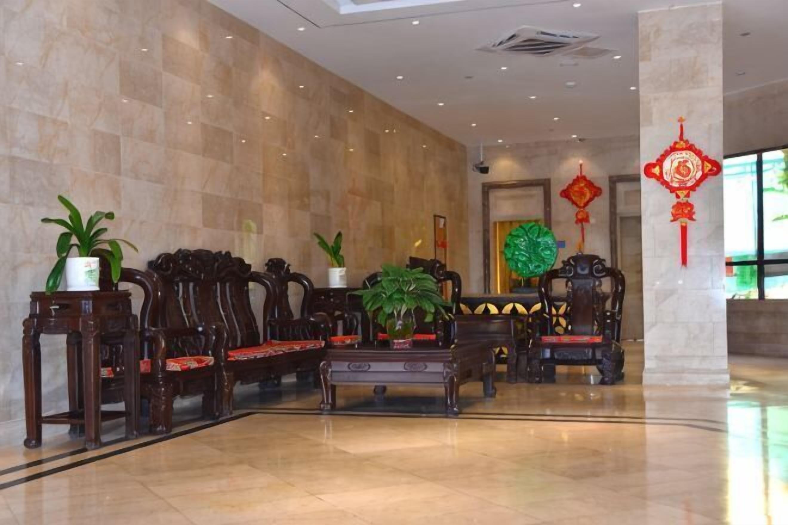 A lobby with marble walls, wooden furniture, and potted plants.