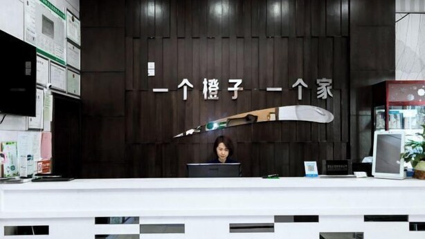 Un mostrador de recepción con un fondo de madera oscura y un letrero con caracteres chinos.